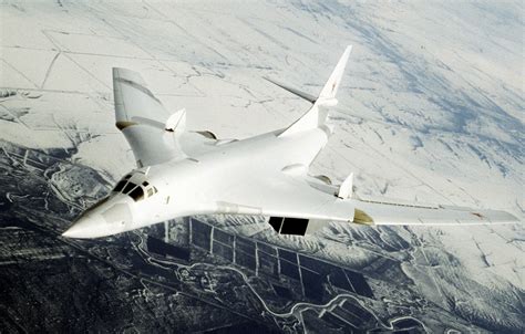 Tupolev Tu-160 Blackjack strategic bomber airborne over snowy landscape