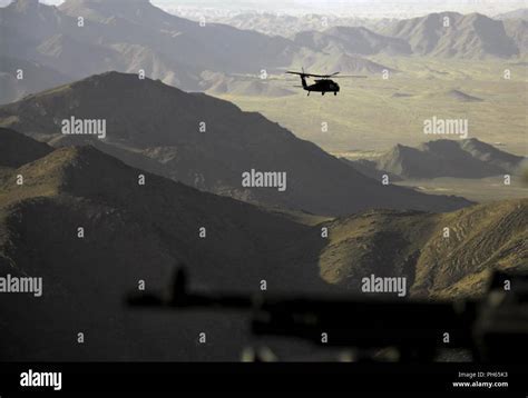 UH-60 Black Hawk flying low over mountainous terrain with troops onboard