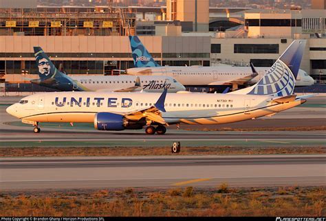 United Airlines Boeing 737 MAX 8 at LAX under overcast skies with ground crew preparing for pushback