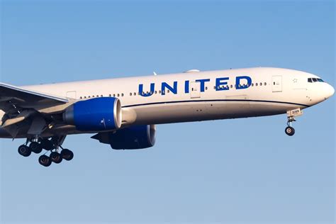 United Airlines Boeing 777-300ER flying over Pacific Ocean sunset