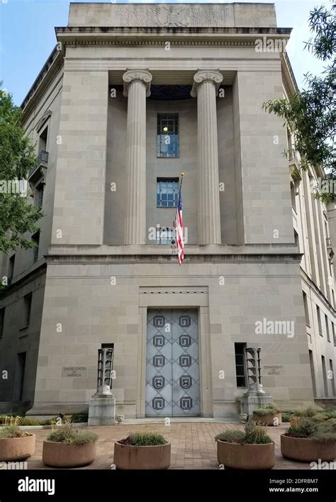 US Department of Justice building exterior in late afternoon light, emphasizing power and secrecy