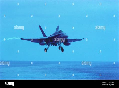 US Navy F/A-18 Hornet approaching carrier deck at sunset