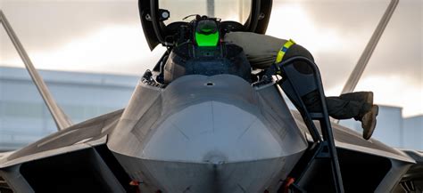 USAF maintenance crew servicing F-22 Raptor avionics systems on flight line