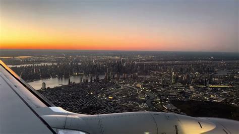 view of Manhattan skyline from airplane approaching LaGuardia Airport during sunset