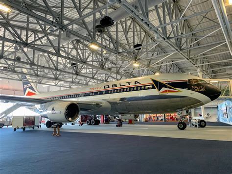visitors walking inside the Delta Flight Museum near the Spirit of Delta aircraft