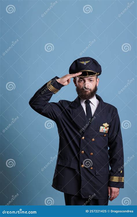 widebody airline captain saluting beside American flag and military transport aircraft
