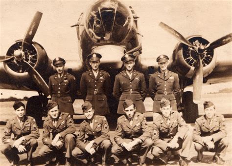 WWII US bomber crew posing proudly in front of plane with extensive mission tallies